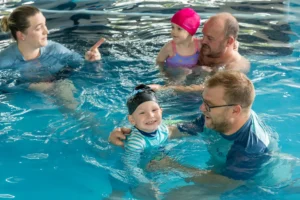 Group baby swim class where parents and instructors guide babies through water play and early water confidence skills